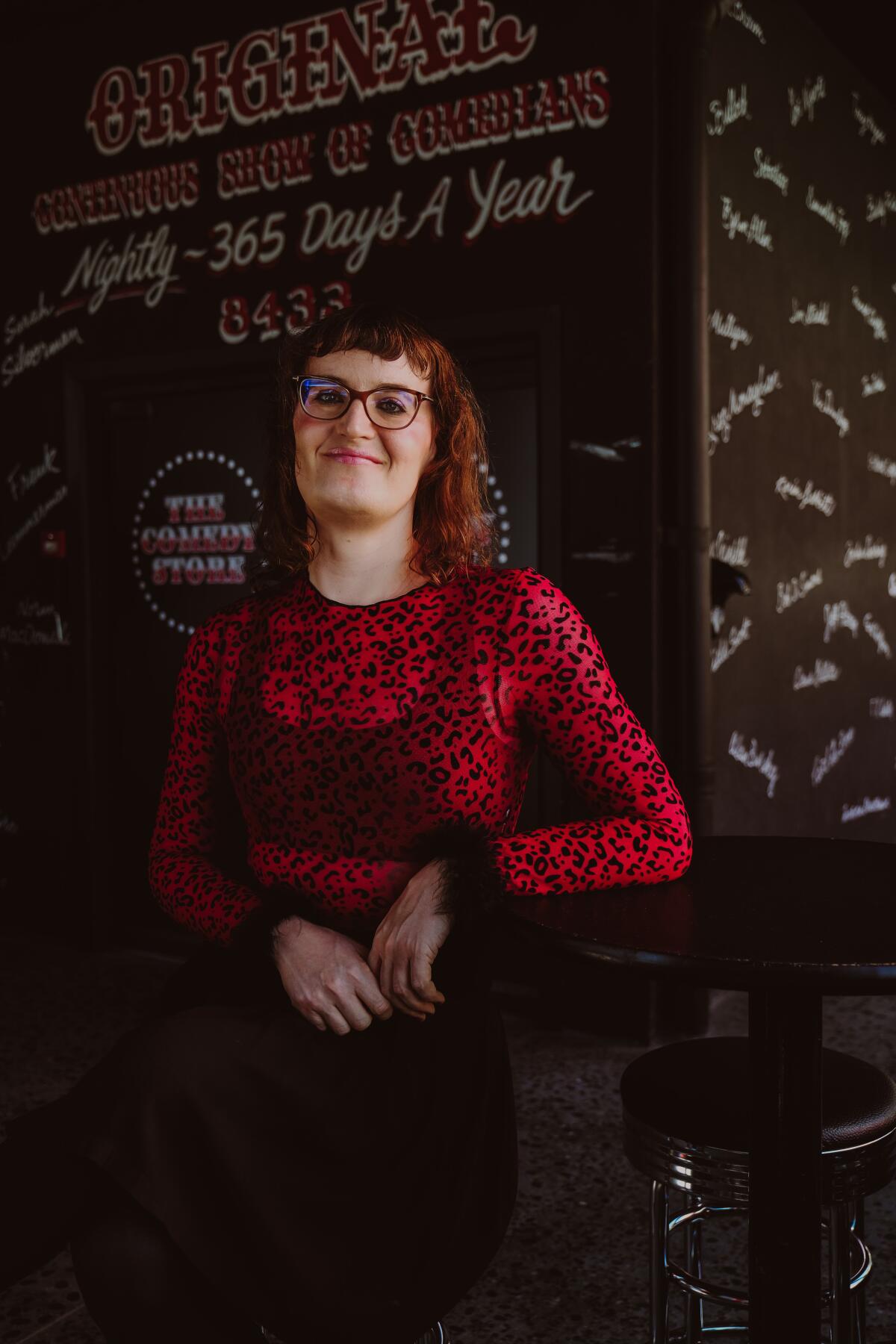 A smiling person wearing glasses and a red top.