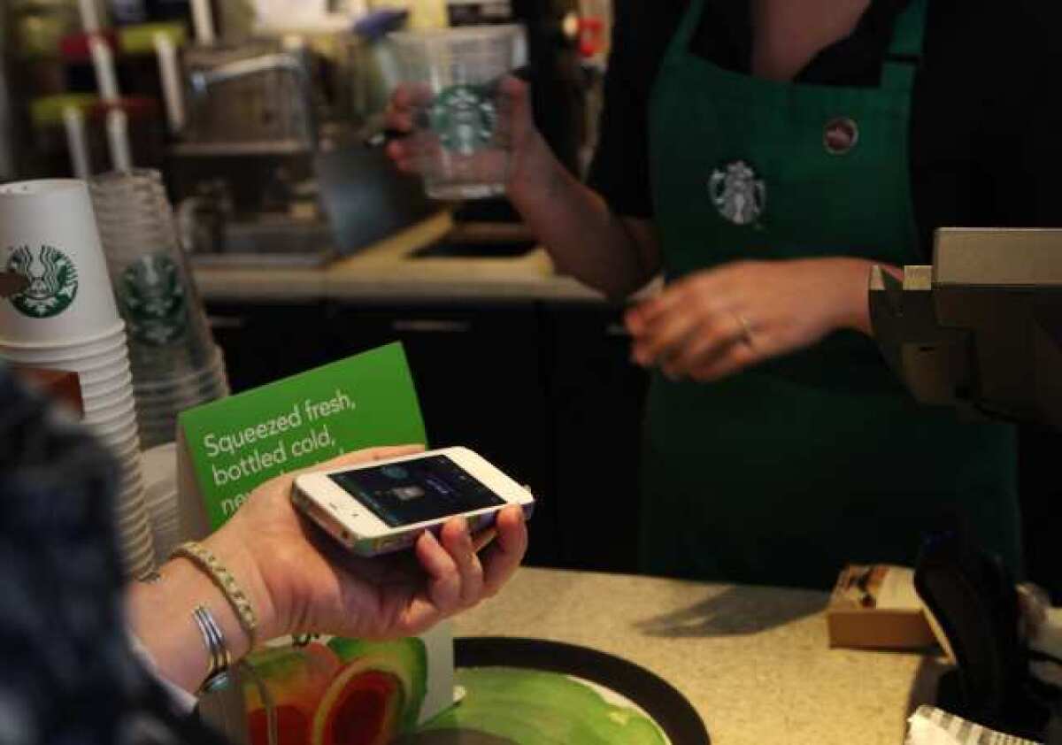 A Starbucks customer uses the Starbucks iPhone app to pay for a coffee at a store in Los Angeles. Starbucks announced a major deal with Square, which will take effect in the fall.