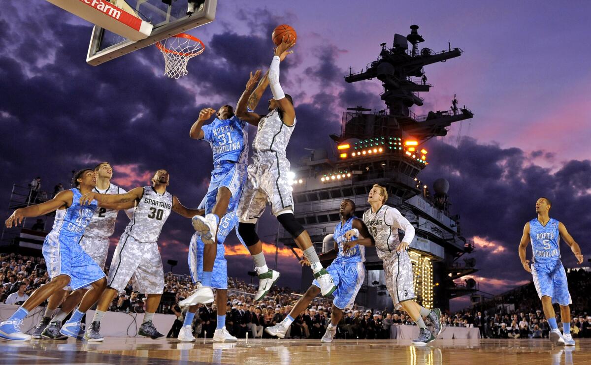 FILE - North Carolina forward John Henson (31) tries to block a shot by Michigan State center Adreian Payne (5) during the first half of the Carrier Classic NCAA college basketball game aboard the USS Carl Vinson in Coronado, Calif., Nov. 11, 2021. Two of the more notable games on Friday’s college basketball schedule are taking place on an aircraft carrier and in a baseball stadium. No. 2 Gonzaga will be facing Michigan State on the flight deck of the USS Abraham Lincoln in the San Diego harbor to celebrate Veterans Day. Wisconsin is playing Stanford at American Family Field, the home of the Milwaukee Brewers. (AP Photo/Mark J. Terrill, File)