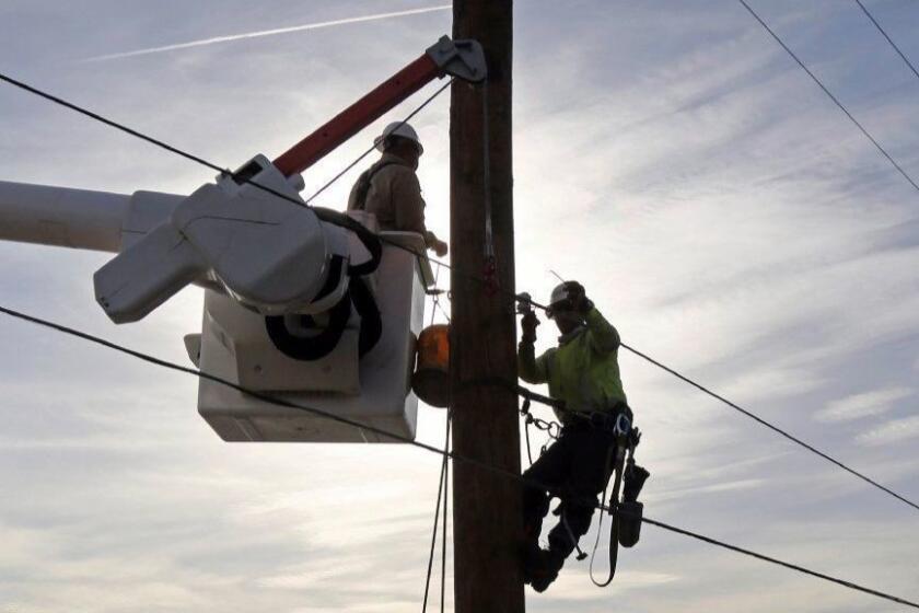 Southern California Edison crews work to replace burned power poles and lines destroyed by the Woolsey Fire over a burned-over hillside along Pacific Coast Highway in Malibu in Southern California Tuesday, Nov. 13, 2018. (AP Photo/Reed Saxon)