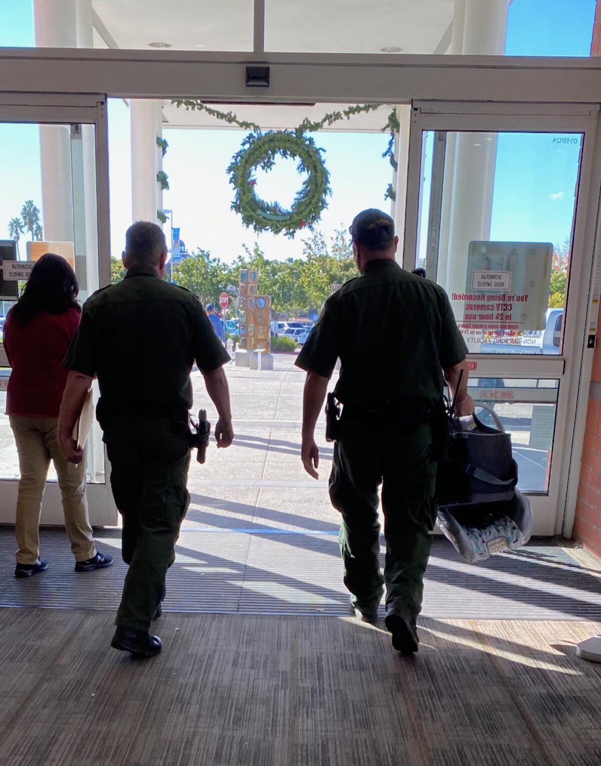 Agentes de la Patrulla Fronteriza salen del hospital Scripps Mercy en Chula Vista con un asiento de bebé para el coche.