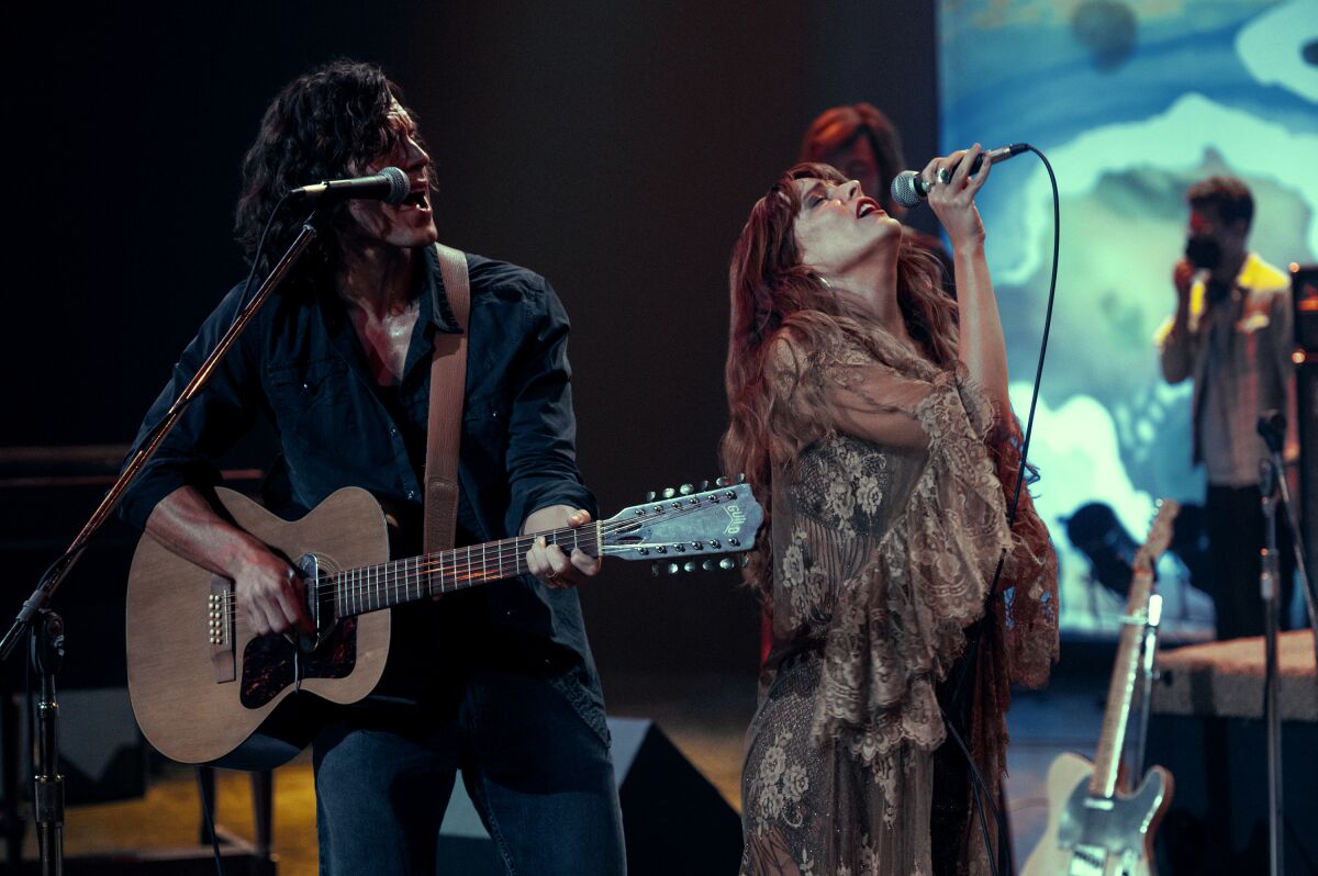 Sam Claflin and Riley Keough perform a song onstage in a scene from "Daisy Jones & the Six."