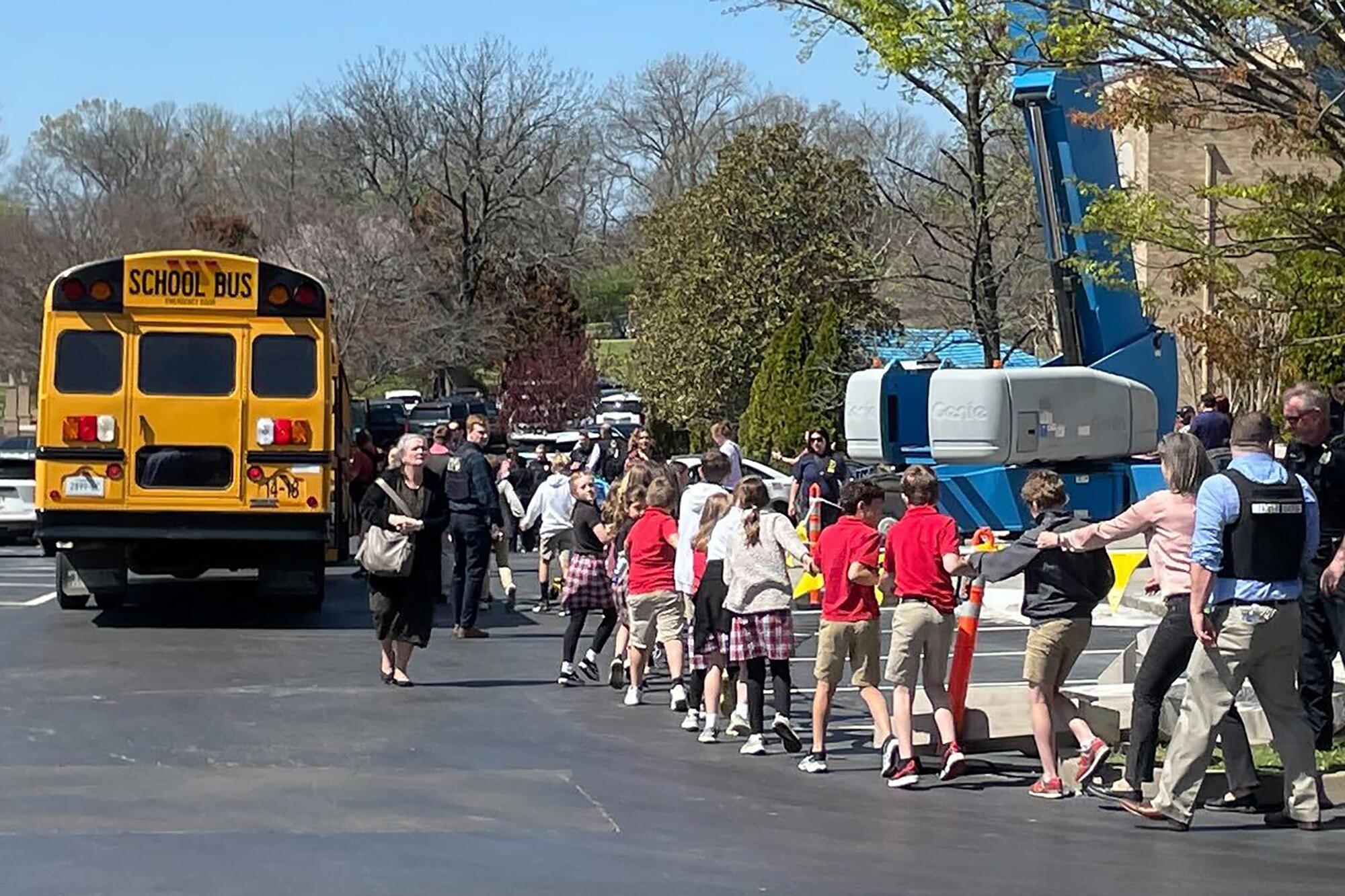 Children line up holding hands outside a school bus.