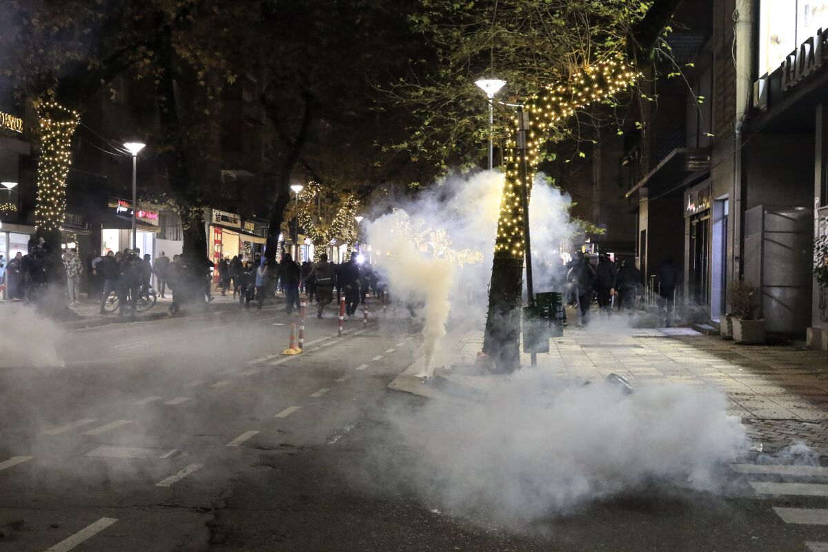 Albanian protesters run away from teargas during a protest rally in Tirana, Saturday, Dec. 12, 2020. Demonstrators in a northern Albanian city damaged the left-wing governing Socialist Party's offices and injured a police officer Saturday, authorities said, as part of ongoing protests this week after a fatal shooting by police enforcing a coronavirus curfew. (AP Photo/Hektor Pustina)