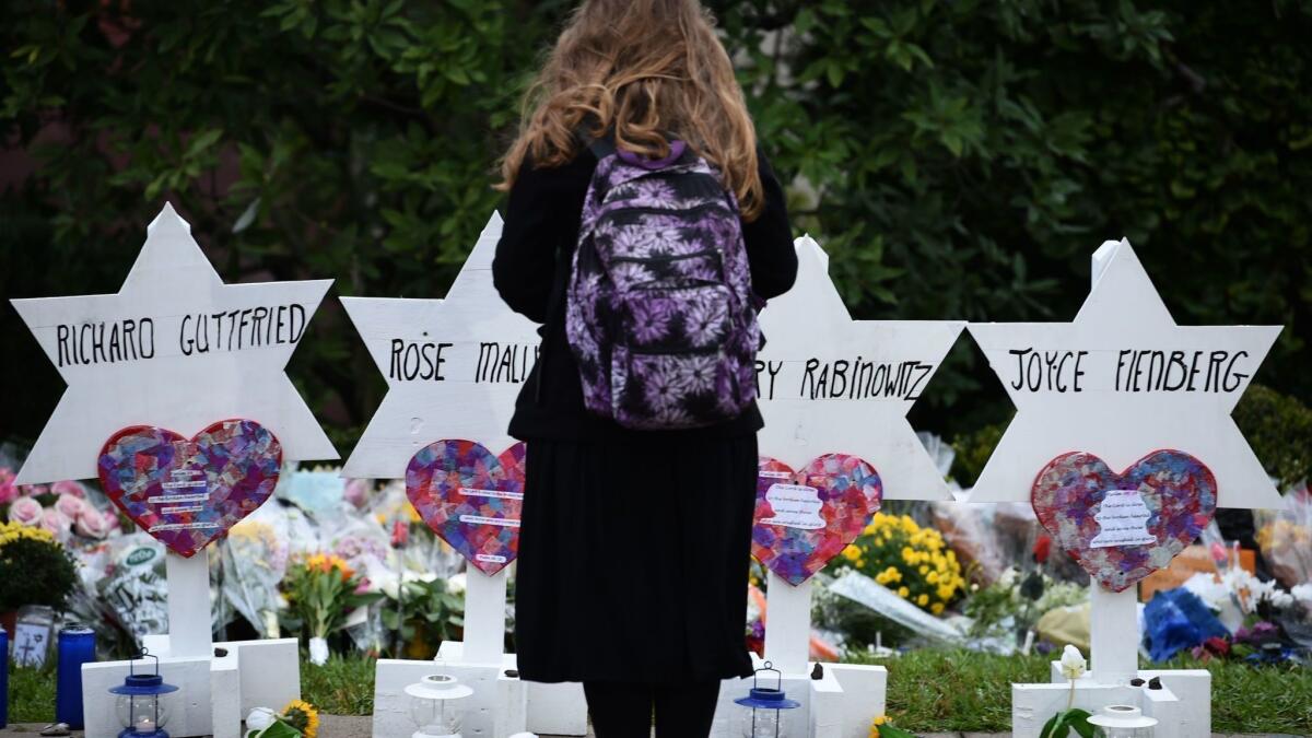 In Pittsburgh, a woman stands before a memorial to the victims of the Oct. 27, 2018, mass shooting at the Tree of Life synagogue. 