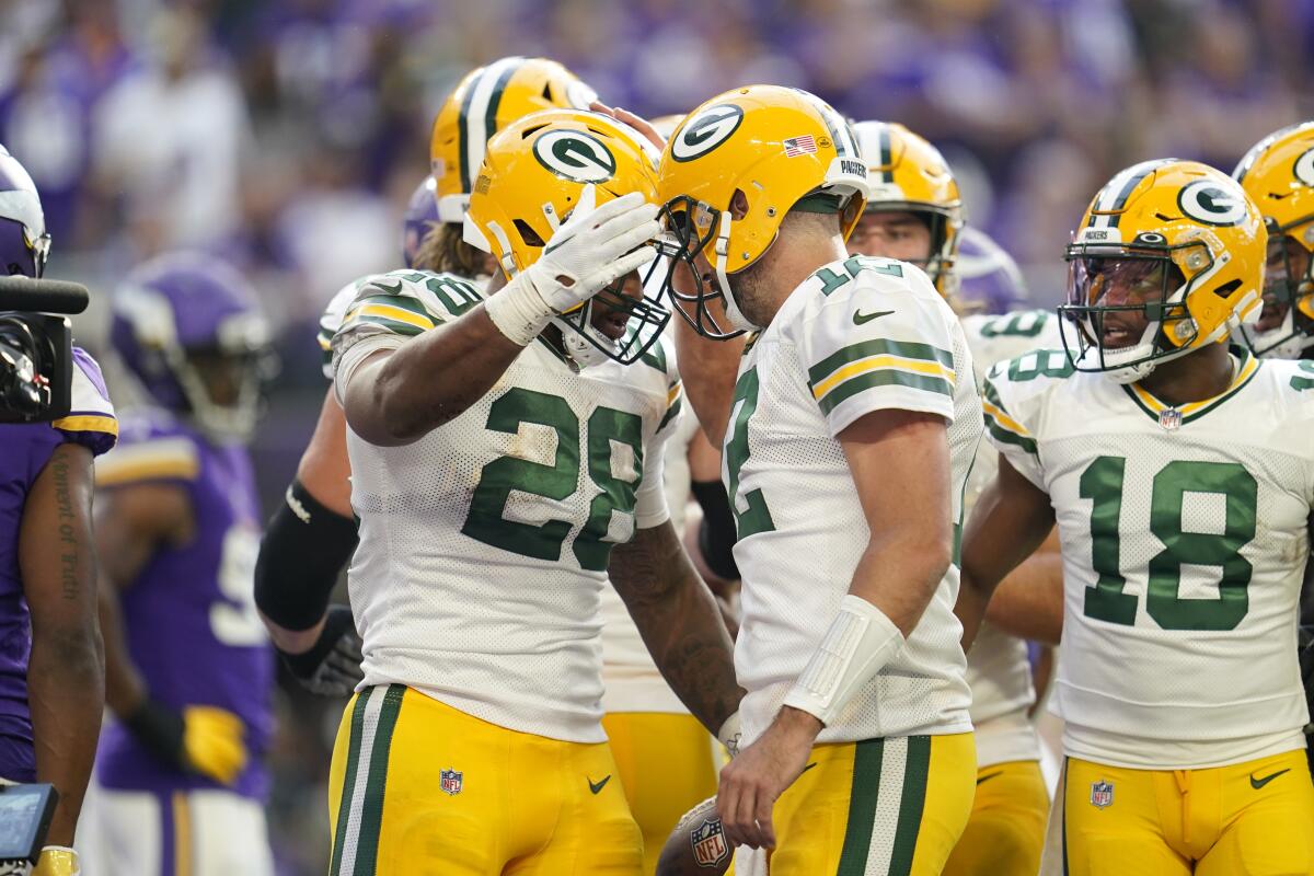 Green Bay Packers running back AJ Dillon (28) celebrates with teammate quarterback Aaron Rodgers (12) after scoring on a 2-yard touchdown run during the second half of an NFL football game against the Minnesota Vikings, Sunday, Sept. 11, 2022, in Minneapolis. (AP Photo/Abbie Parr)