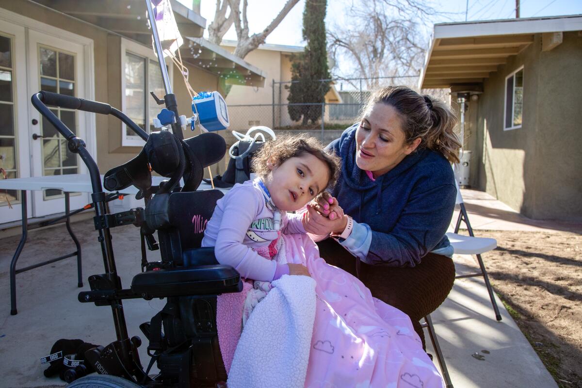 Amber Suarez sits with her 3-year-old daughter Mia, who needs the care of home nurses.