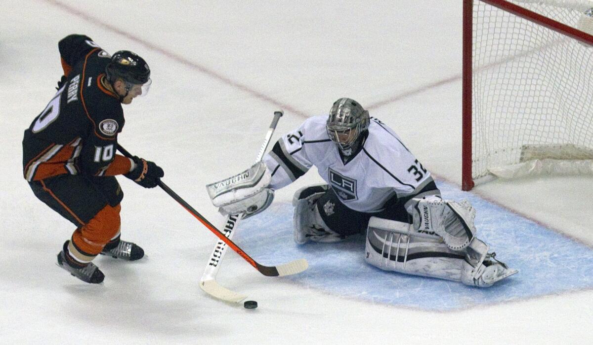 Kings goaltender Jonathan Quick pokes the puck away from Ducks left wing Corey Perry to prevent a penalty shot in the first period.