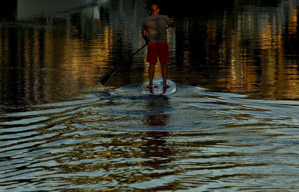 A paddleboarder navigates the canals of Naples, a bayside community in Long Beach.