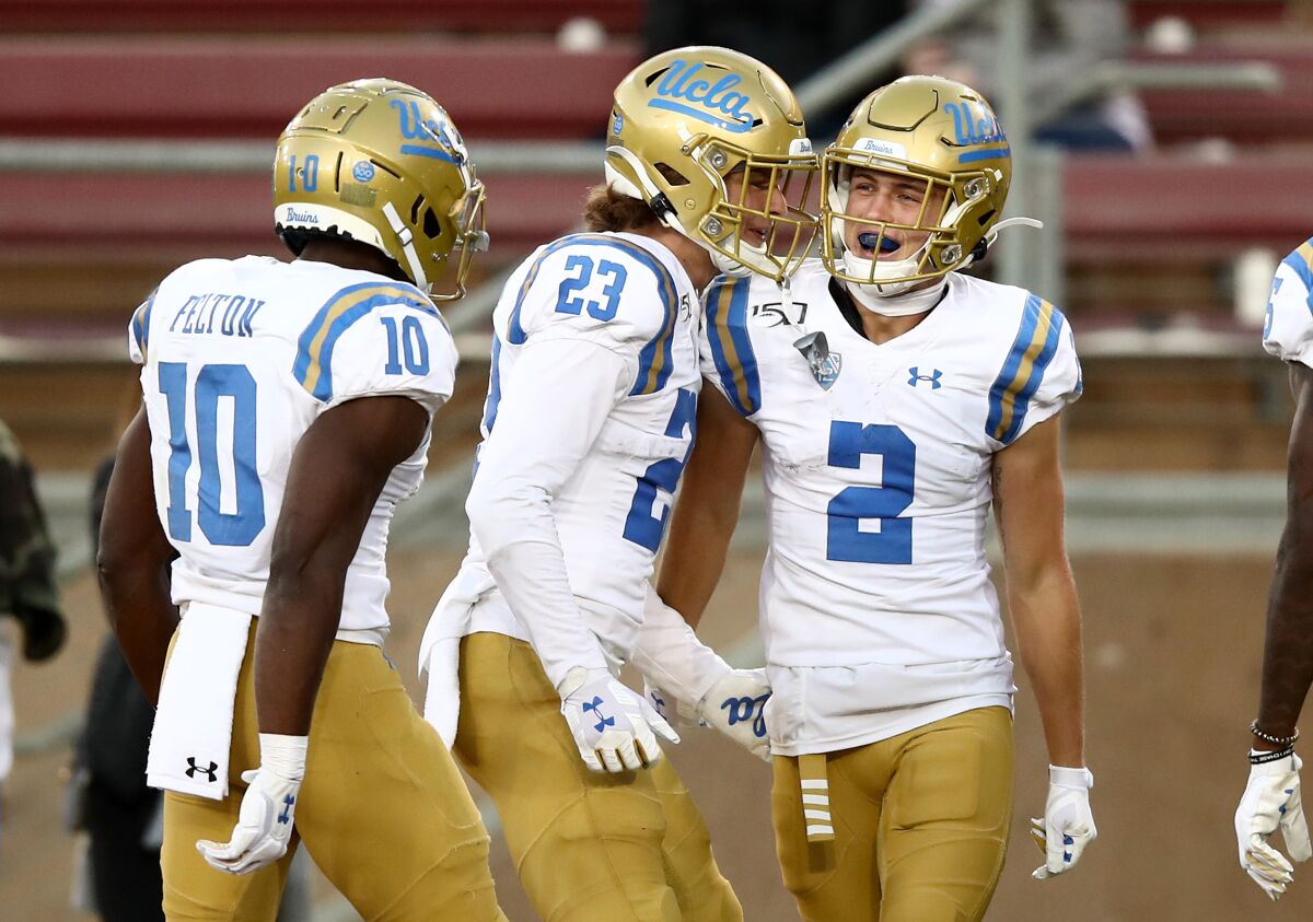 UCLA's Kyle Philips (2) is congratulated by Chase Cota (23) and Demetric Felton (10) after he scored a touchdown against Stanford on Oct. 17 in Palo Alto.