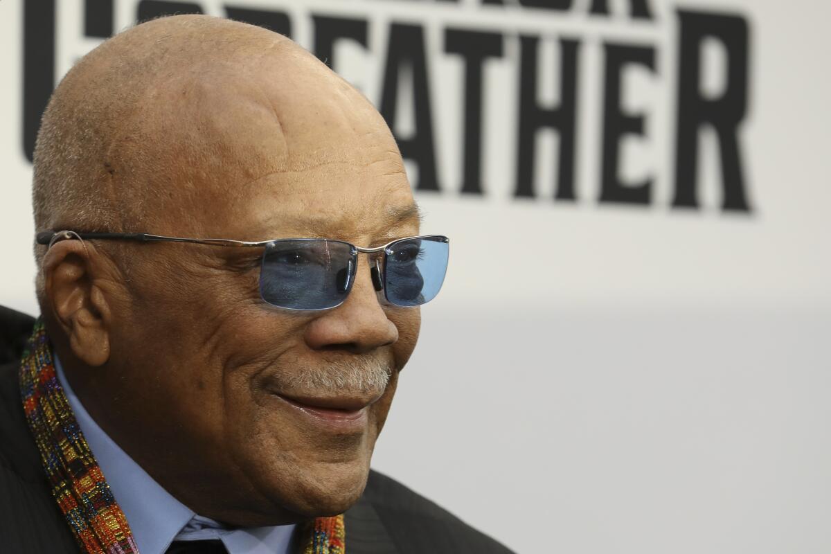 Quincy Jones smiles in blue-tinted glasses.