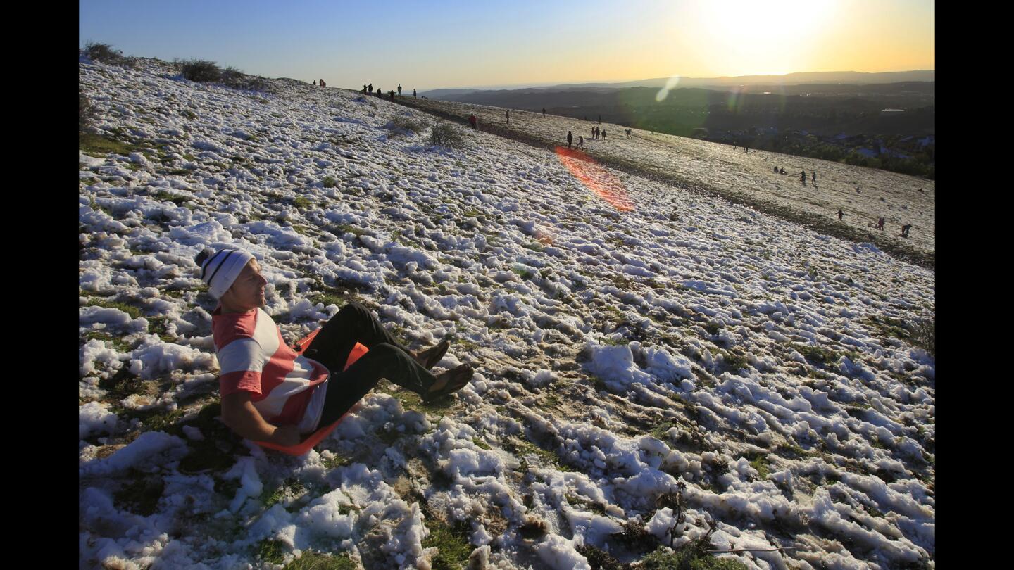 A rare sight in Southern California leads Ryan Schulenburg, 19, of Foothill Ranch, to go sledding in his beach sandals on a hillside in Robinson Ranch.