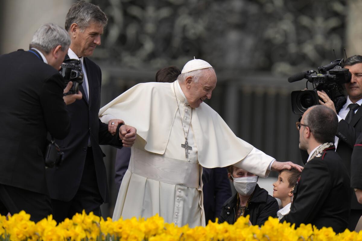 El papa Francisco acaricia la cabeza de un niño al final de su audiencia general semanal 