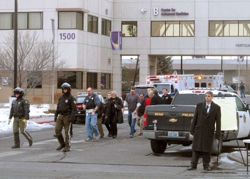 Police escort staff members and others away from a medical center in Reno after a gunman killed one person and wounded two others before shooting himself.