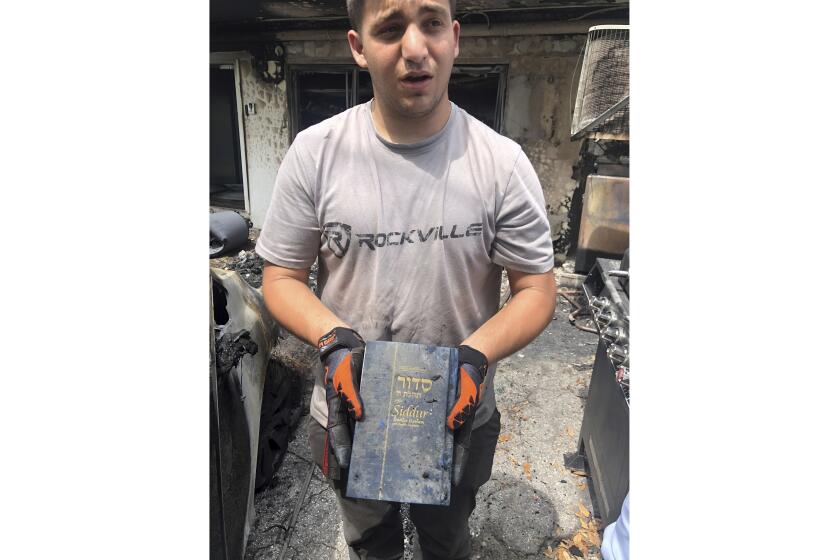 A Jewish prayer book is displayed by Jordan Meshel after it survived inside a minivan that was destroyed by an arson fire at the Las Olas Jewish Center on Saturday, March 16, 2024, Fort Lauderdale, Fla.. (Rabbi Chaim Slavaticki via AP)