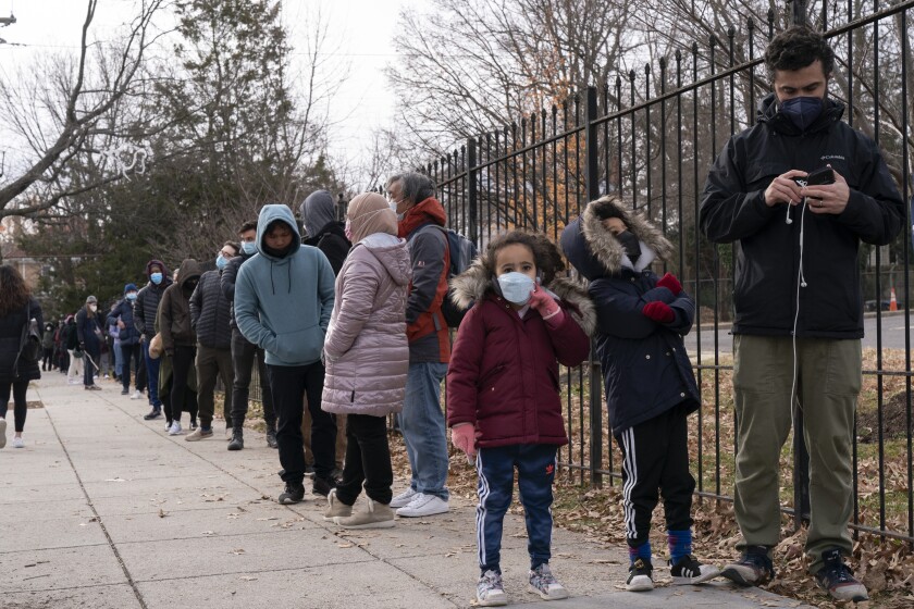 Unos niños esperan con sus padres en una fila para pruebas de coronavirus, en Washington.