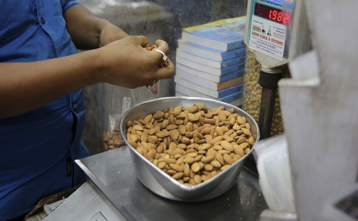 A shopkeeper weighs almonds for a customer. Almonds used to have about 170 calories per serving, then researchers said a serving had fewer than 130. The shifting numbers show how the figures on nutrition labels may not be precise.