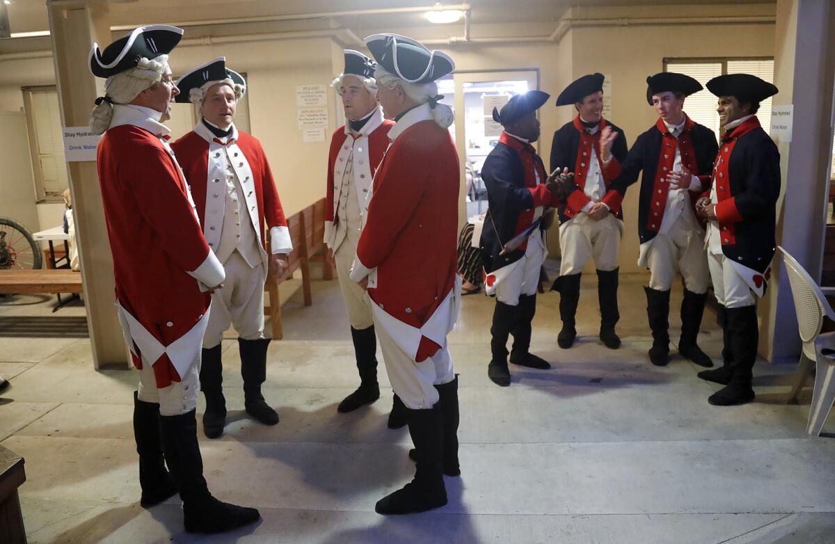 Cast members dressed as British redcoats, left, and American revolutionary soldiers, wait backstage.