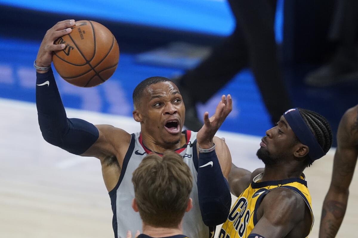 Washington Wizards' Russell Westbrook goes to the basket against Indiana Pacers' Caris LeVert (22) during the first half of an NBA basketball game Saturday, May 8, 2021, in Indianapolis. (AP Photo/Darron Cummings)