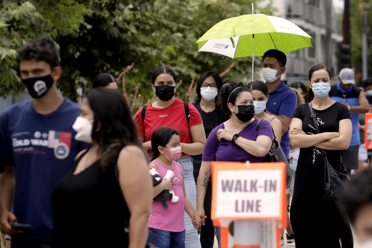 People wearing masks wait in line