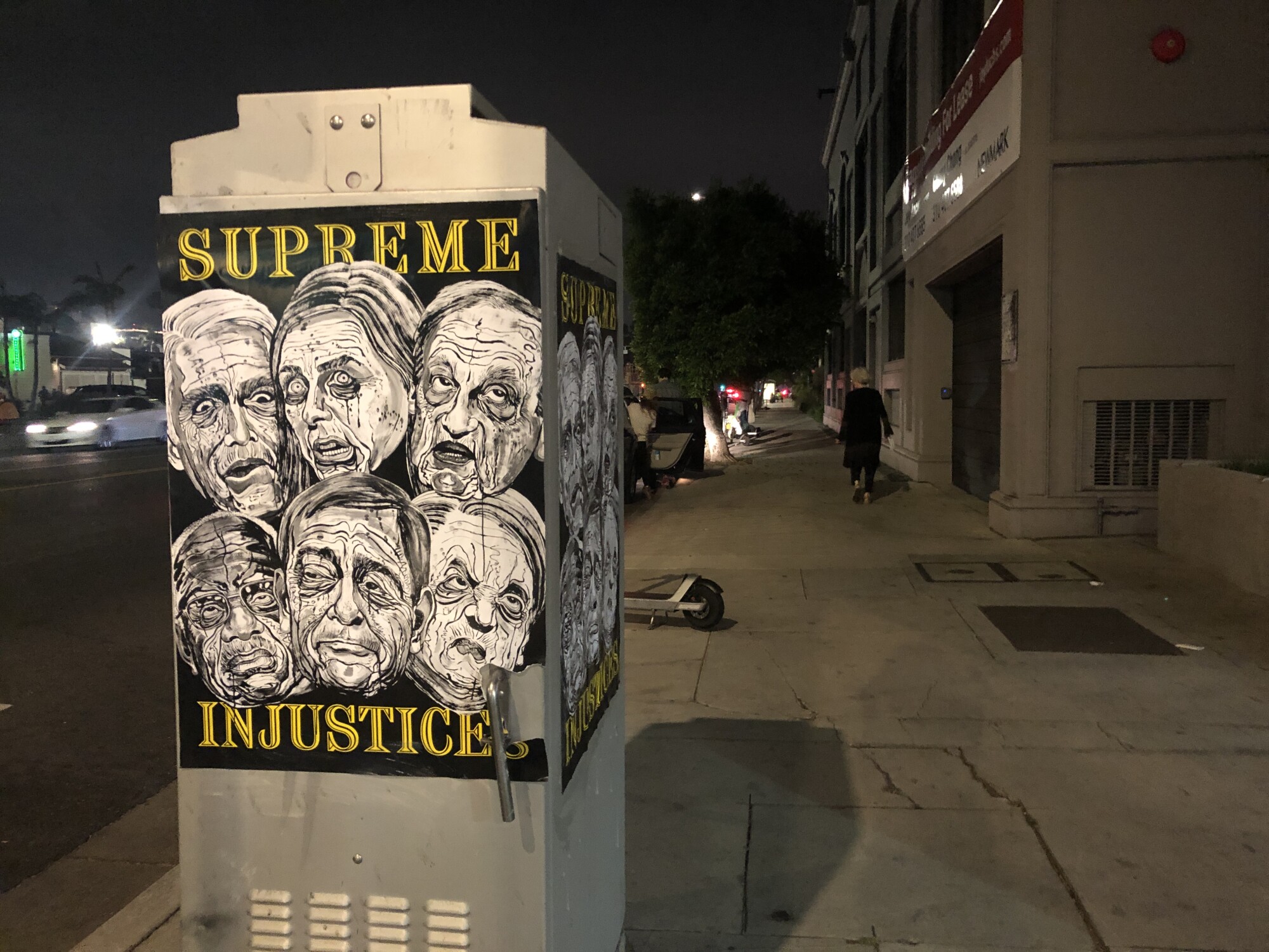 A poster that shows six members of the Supreme Court  that overturned Roe v. Wade, pasted to an electrical box at night.