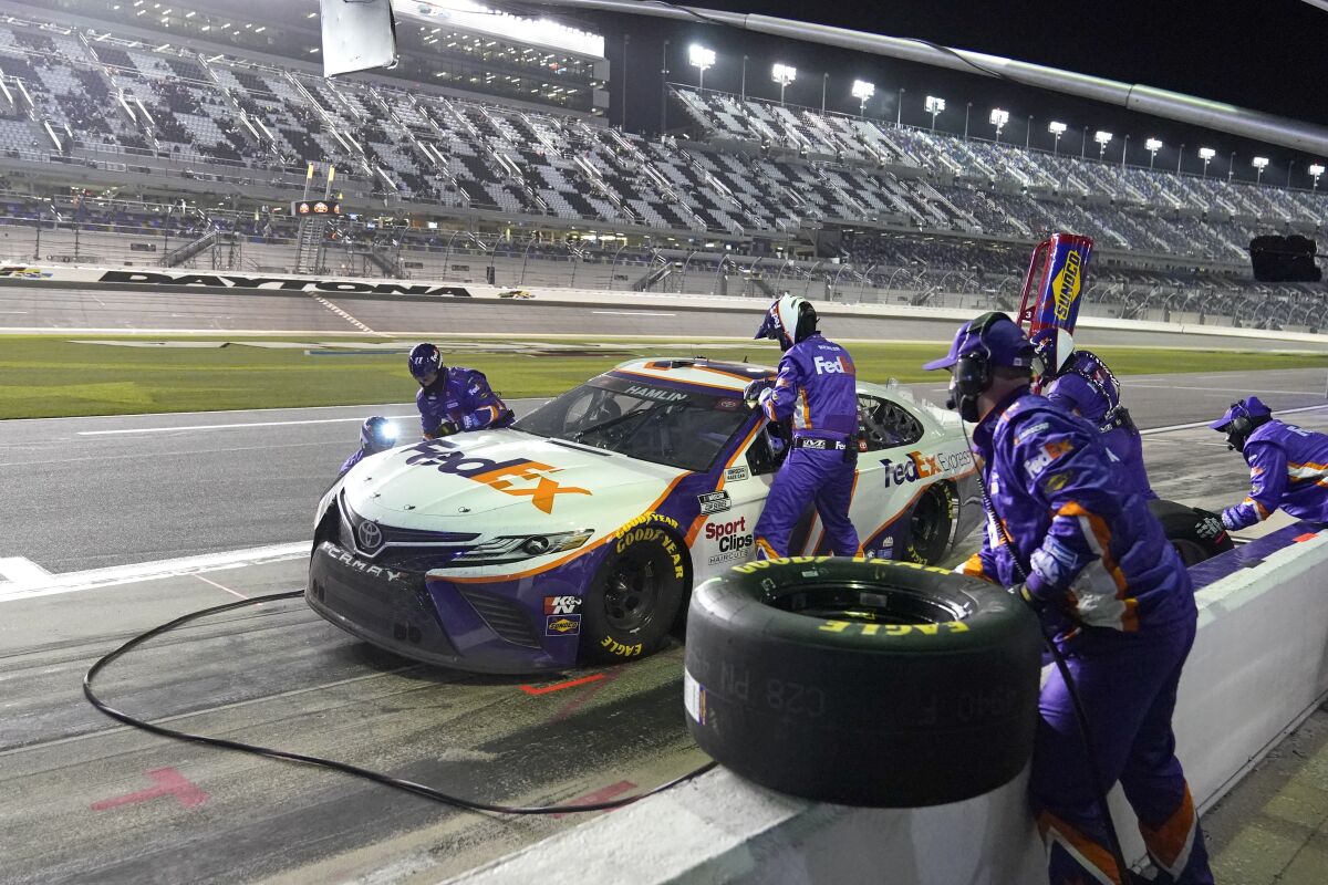 Denny Hamlin's crew changes tires and adds fuel during a pit stop in the 2021 NASCAR Clash at Daytona International Speedway.