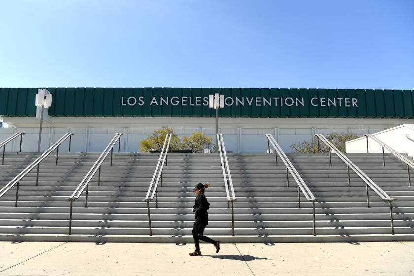 LOS ANGELES, CALIFORNIA MARCH 30, 2020-A jogeer runs past the L.A. Convention Center where it will become a field hospital to help relieve the pressures brought on by the novel coronavirus pandemic. (Wally Skalij/Los Angeles Times)