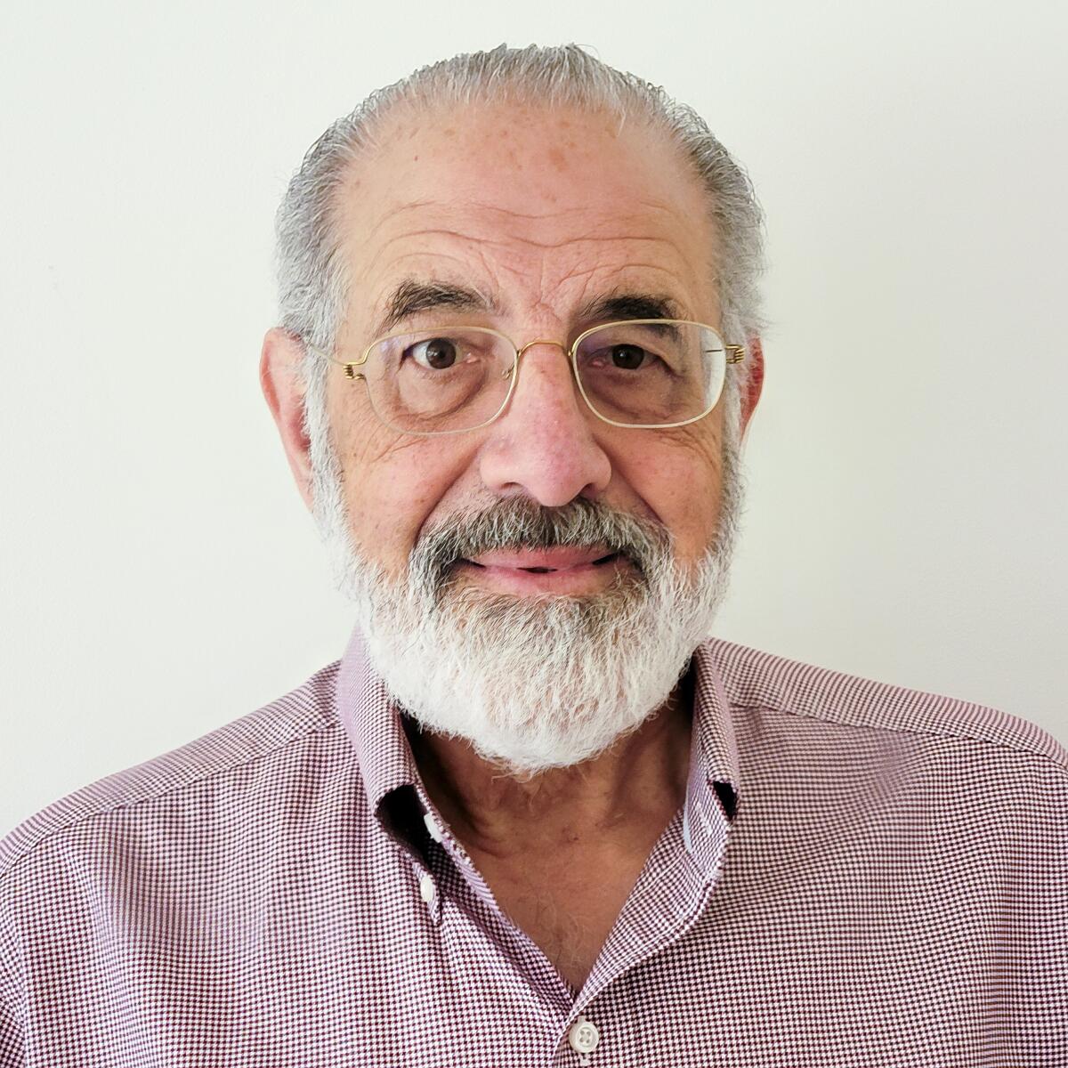 A man with a beard and eyeglasses, pictured from the shoulders up