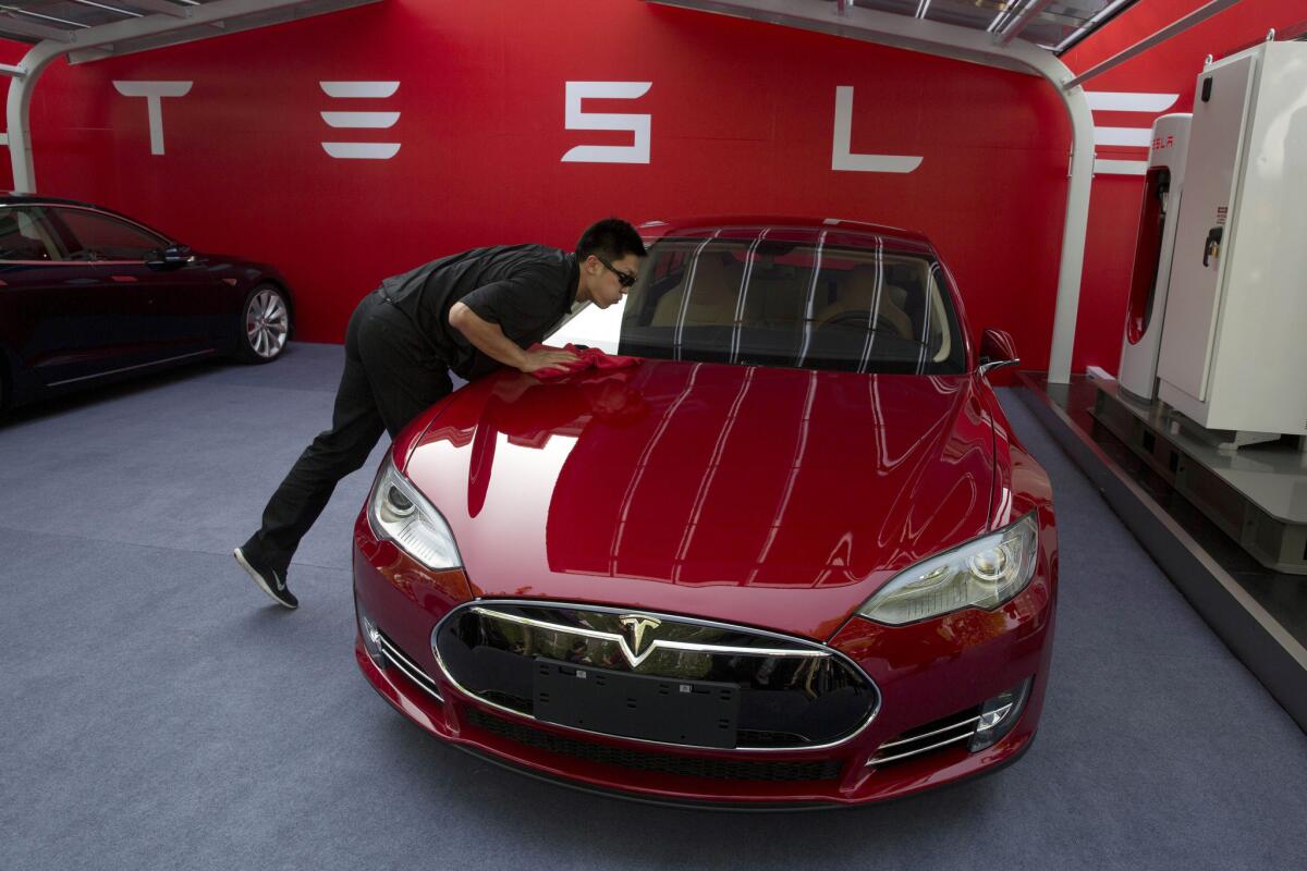 Tesla Motors has partnered with Panasonic Corp. to make batteries in America for the California-based electric car manufacturer. In this April 22 file photo, a worker cleans a Tesla Model S sedan before an event to deliver the first set of cars to customers in Beijing.