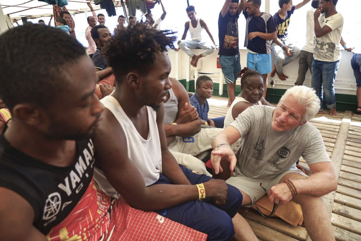 El actor Richard Gere (d) conversa con migrantes a bordo del buque humanitario Open Arms en el Mediterráneo