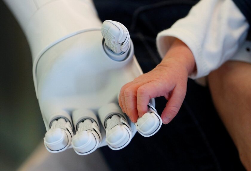 New recruit "Pepper" the robot, a humanoid robot designed to welcome and take care of visitors and patients, holds the hand of a new born baby at AZ Damiaan hospital in Ostend, Belgium.