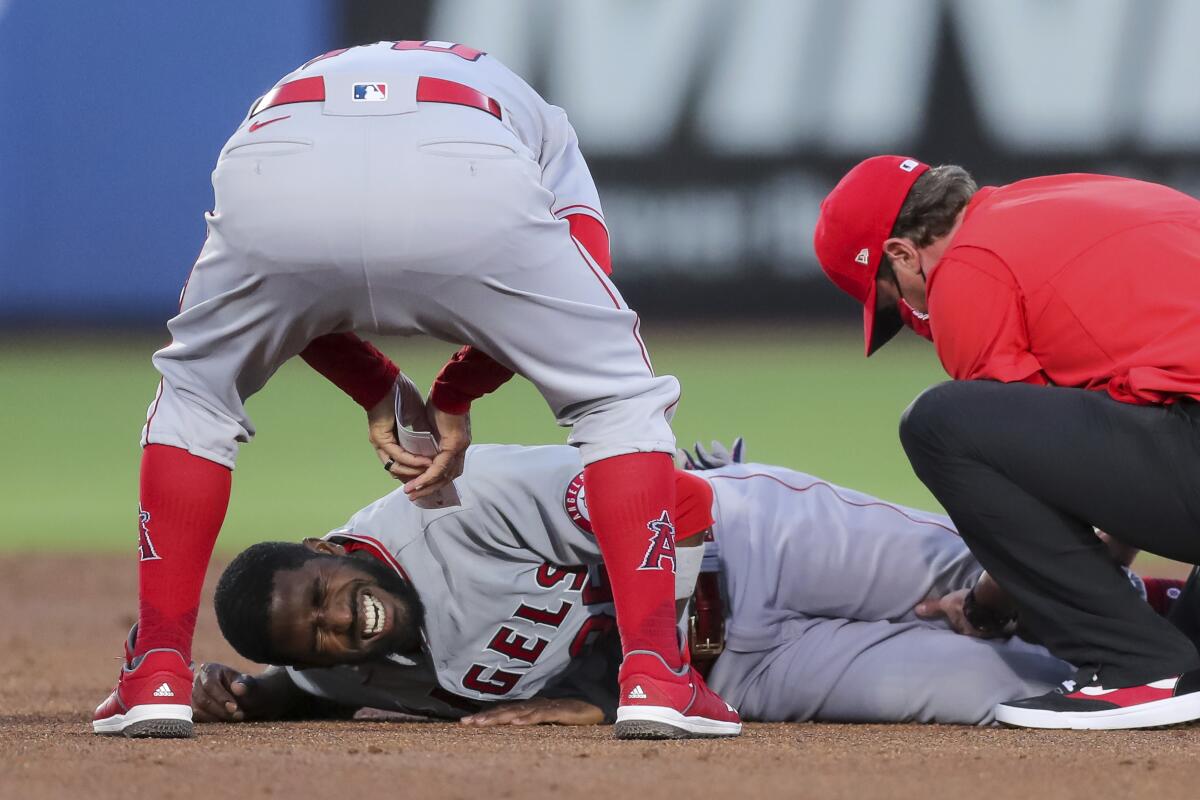 Los Angeles Angels manager Joe Maddon, top, leans over to check on Dexter Fowler who was injured during a play at second base against the Toronto Blue Jays during the second inning of a baseball game Friday, April 9, 2021, in Dunedin, Fla. (AP Photo/Mike Carlson)