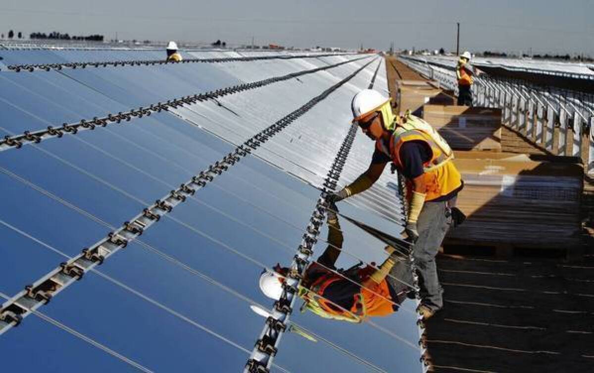 A worker installs a photovoltaic panel at the Tenaska Imperial Solar Energy South project in the Imperial Valley west of El Centro, Calif.