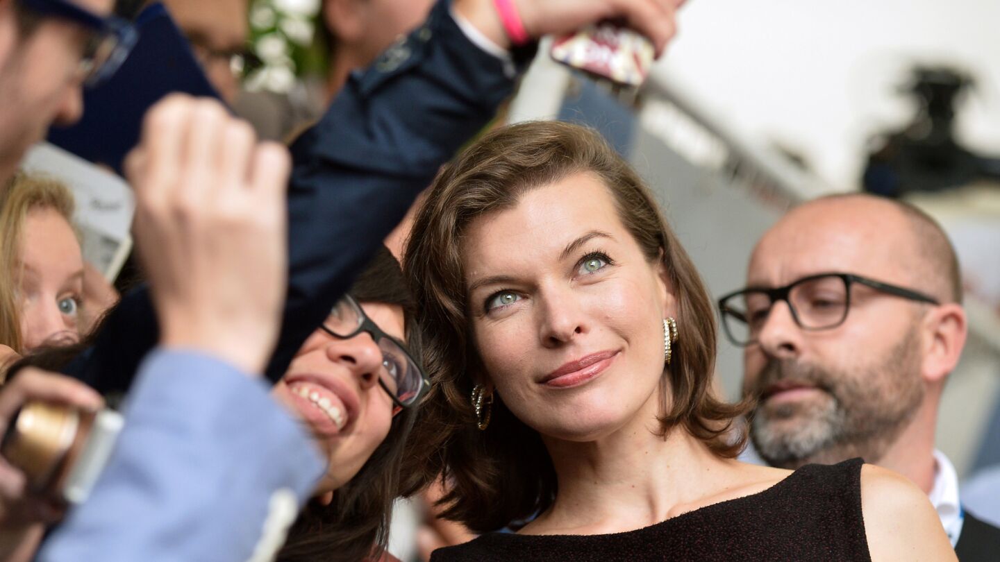 Actress Milla Jovovich poses for a selfie with fans as arrives for the press conference of the movie "Cymbeline" presented in the Orizzonti selection at the 71st Venice Film Festival on September 3, 2014 at Venice Lido.