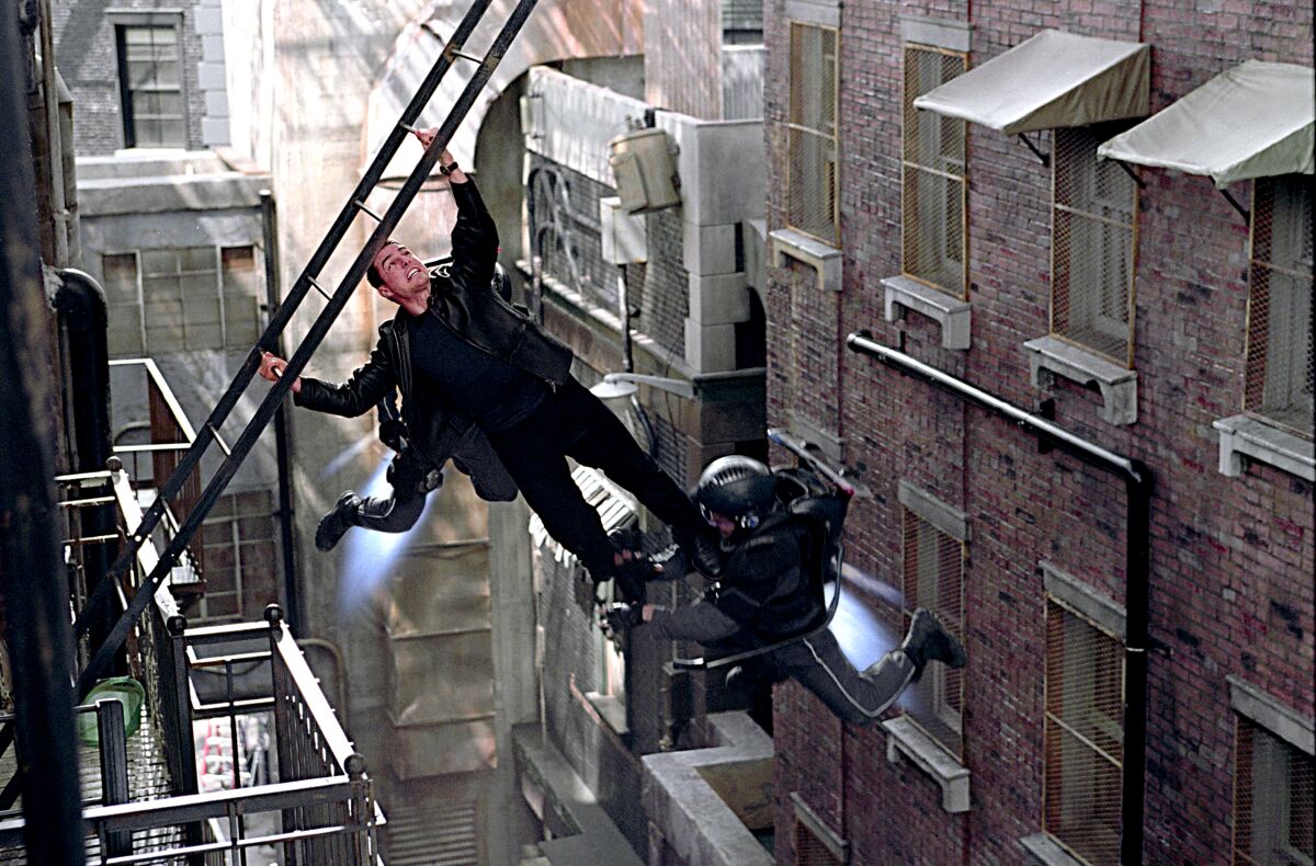 Tom Cruise hangs from a fire escape ladder in a tenement alley in a scene from "Minority Report."