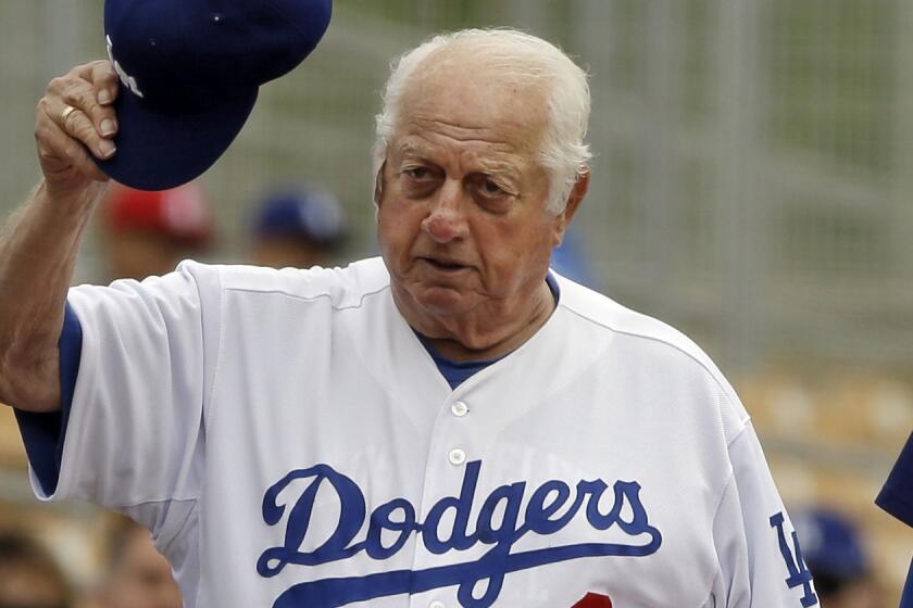 Former Dodgers manager Tommy Lasorda acknowledges the fans as he walks to the dugout before a spring exhibition game against the Cleveland Indians in Glendale, Arizona, on March 3, 2013.