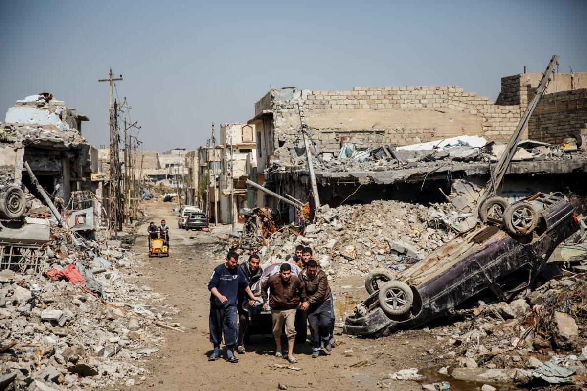 People move quickly to avoid danger along the destroyed streets in Mosul after an airstrike attributed to the U.S. killed scores of people in Iraqi city.