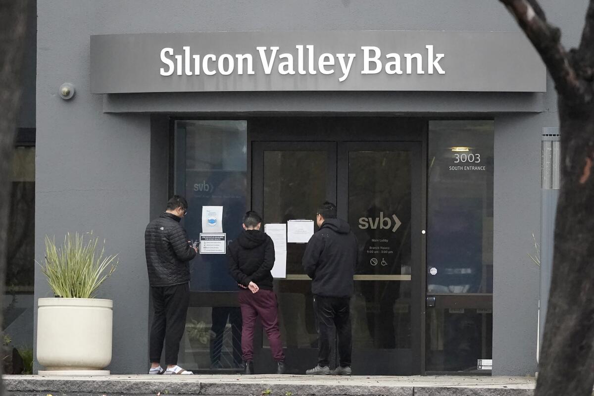 People look at signs posted outside of an entrance to Silicon Valley Bank.