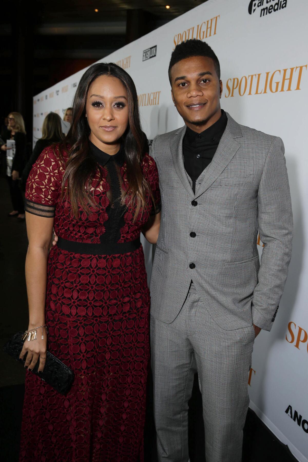 A woman in a red dress and a man in a gray suit stand and pose together