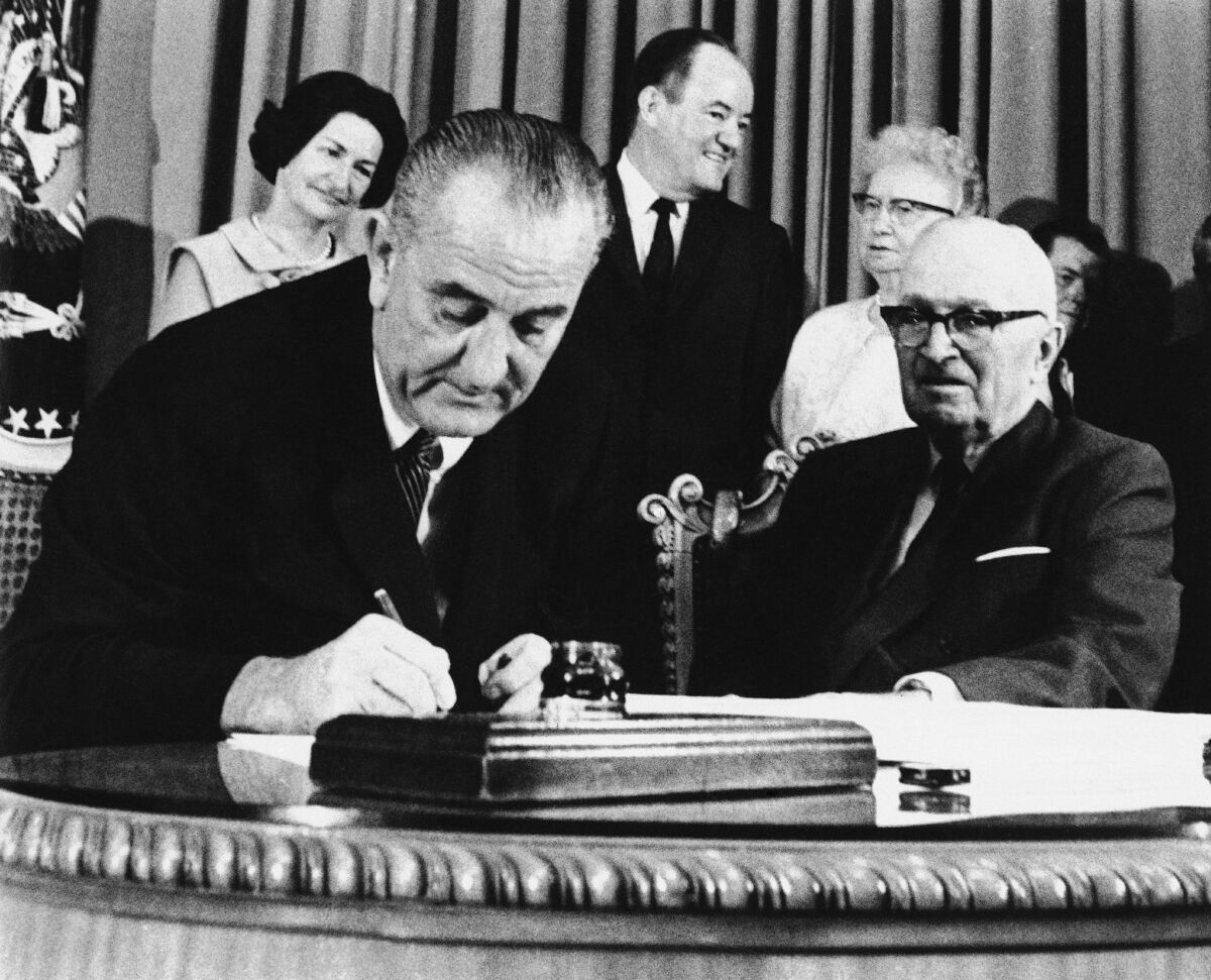 President Harry S. Truman, right, witnesses President Lyndon B. Johnson sign the Medicare Bill in Independence, Missouri July 30, 1965.