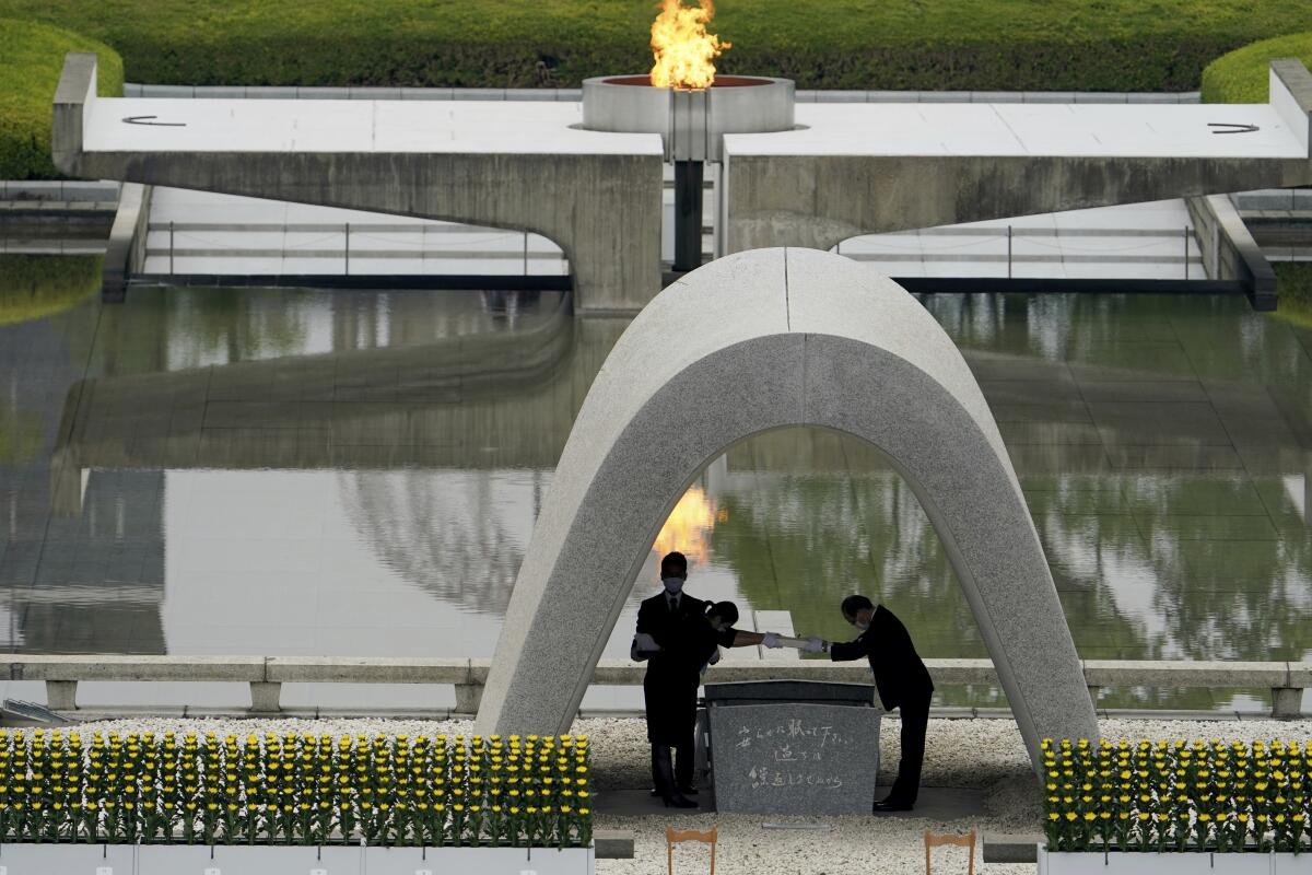 Two men, one standing and one bowing, pictured under a memorial arch.