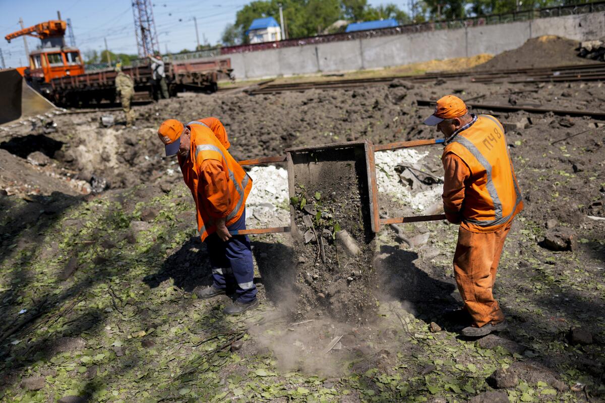 Workers removing debris next to crater