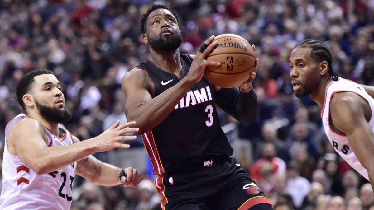 Heat guard Dwyane Wade splits the defense of Raptors guard Fred VanVleet (23) and forward Kawhi Leonard during the second half Sunday.