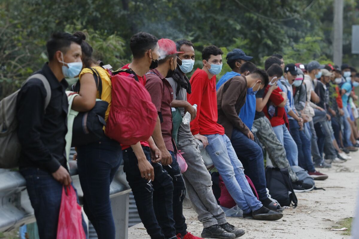 Migrants trying to reach the U.S. border rest at the edge of a highway as they await rides on passing vehicles, near Choloma, Honduras, Thursday, Jan. 14, 2021. About 200 Honduran migrants resumed walking toward the border with Guatemala early Thursday, a day before a migrant caravan was scheduled to depart the city of San Pedro Sula. (AP Photo/Delmer Martinez)