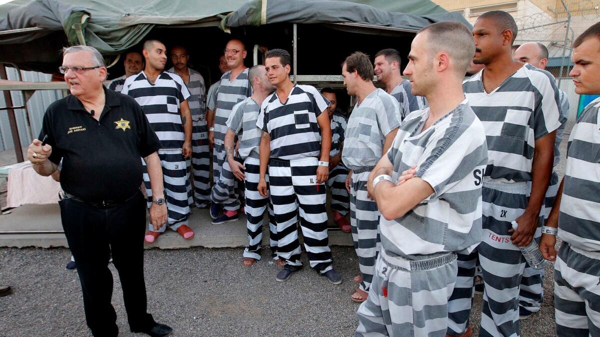 In this June 23, 2012, file photo, inmates gather next to Maricopa County Sheriff Joe Arpaio as he walks through the Tent City jail complex.