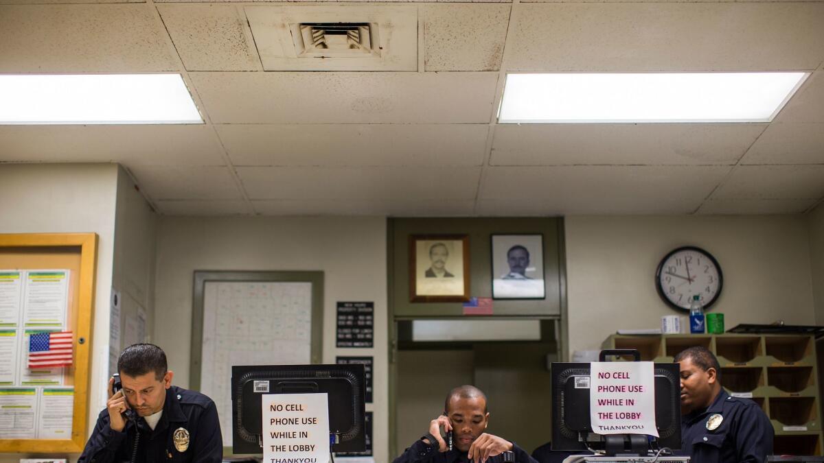 LAPD officers answer phones in the lobby of the Southeast Community Police Station, which has been found to have black mold on the ceiling HVAC vents.