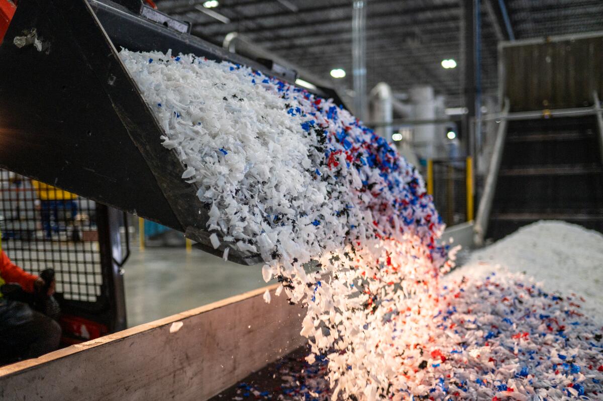 White, red and blue bits of plastic are loaded onto a conveyor belt