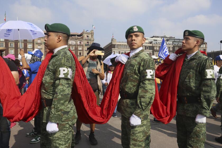 Members of Mexico's military hold the Mexican flag before an opposition rally at the Zocalo, Mexico City's main square, Sunday, May 19, 2024. (AP Photo/Ginnette Riquelme)