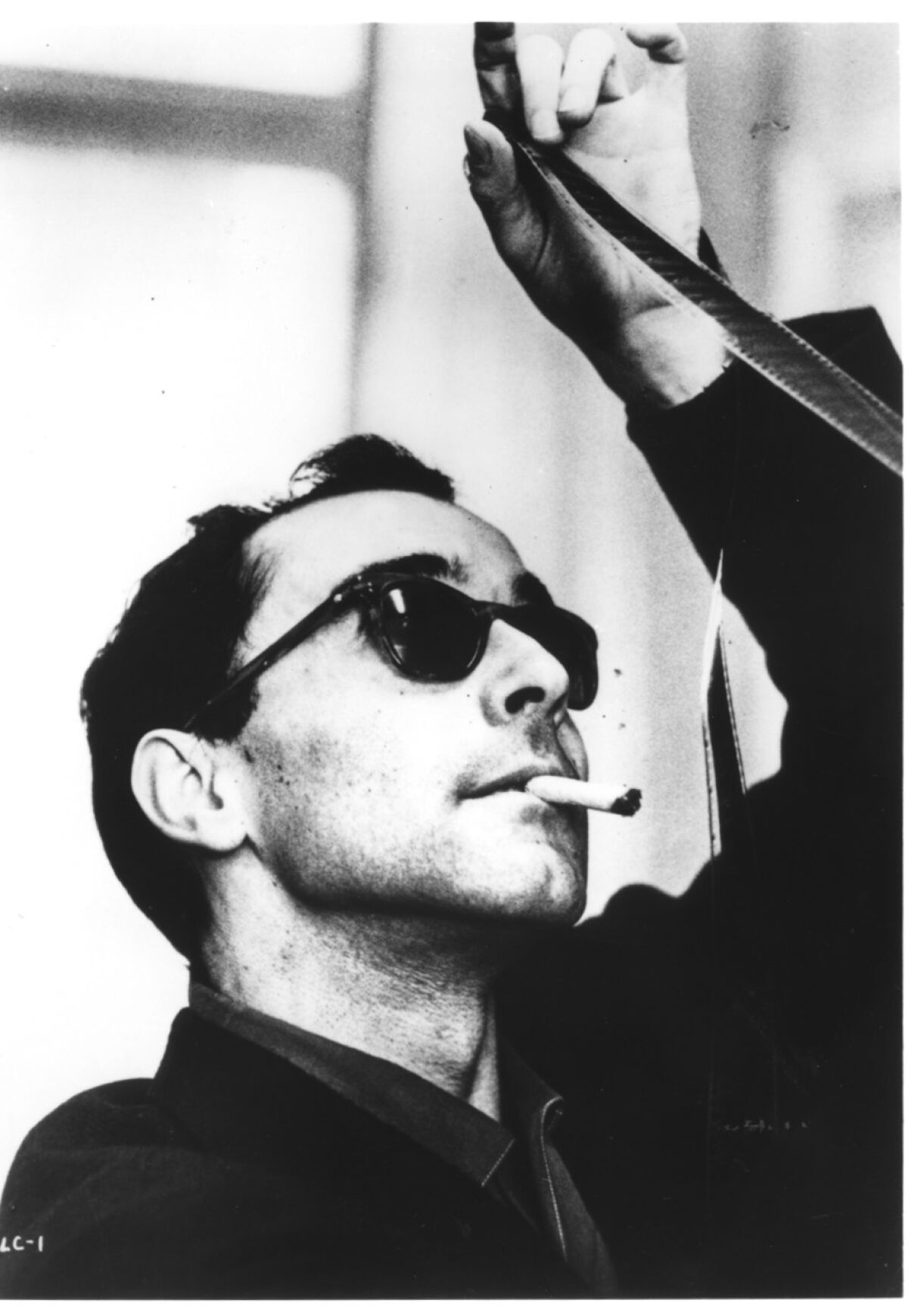 Director Jean-Luc Godard looks over film footage 