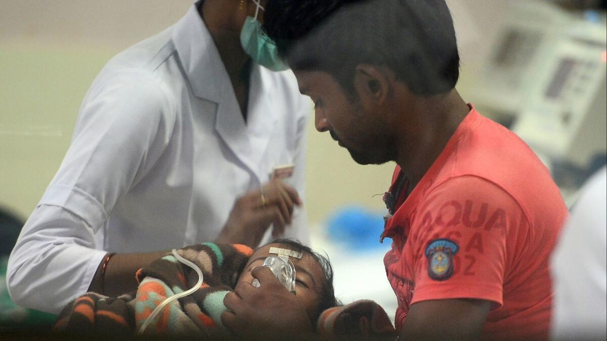 Medical staff and relatives attend to a child admitted in the encephalitis ward at the Baba Raghav Das Hospital in Gorakhpur, India, on Aug. 12, 2017.